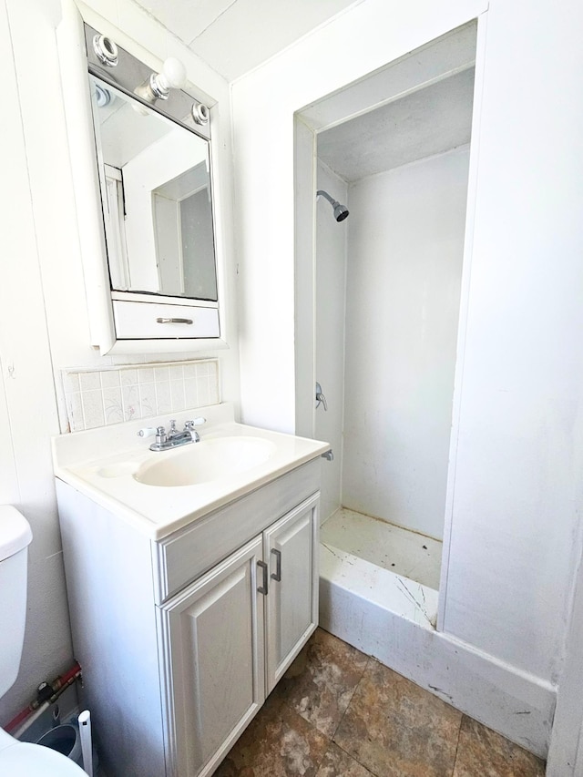 bathroom with vanity, toilet, and a shower