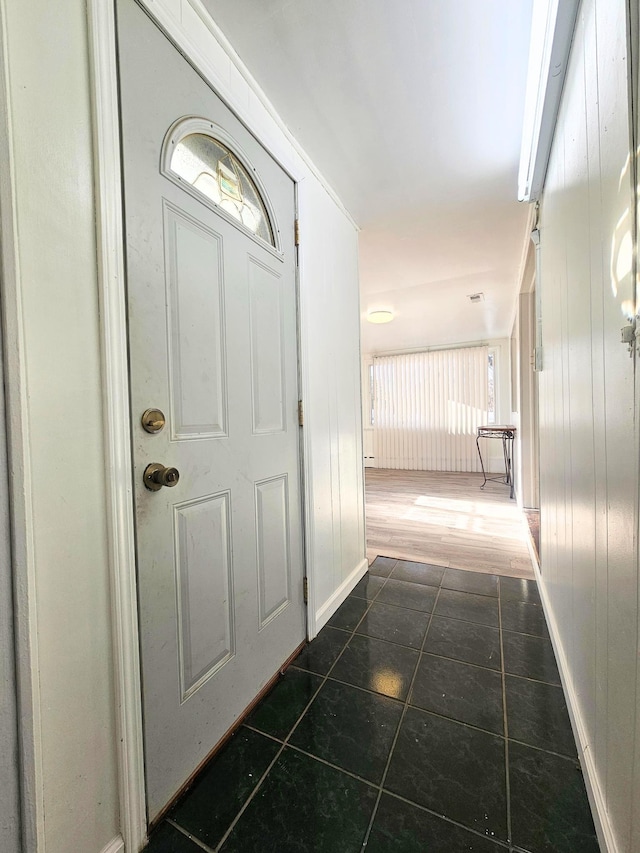 entrance foyer featuring dark tile patterned flooring and wooden walls