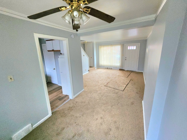 carpeted foyer with ceiling fan and ornamental molding