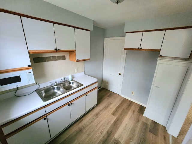 kitchen featuring white cabinets, light hardwood / wood-style floors, sink, and tasteful backsplash