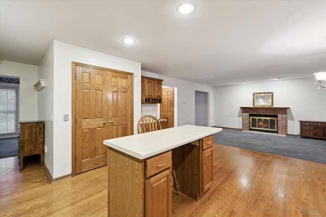 kitchen featuring a center island, light hardwood / wood-style floors, a notable chandelier, and a brick fireplace