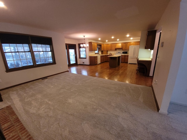 unfurnished living room featuring dark colored carpet and a chandelier