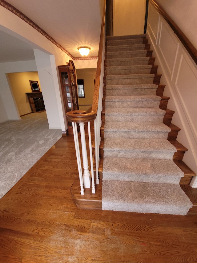 stairs featuring wood-type flooring and ornamental molding