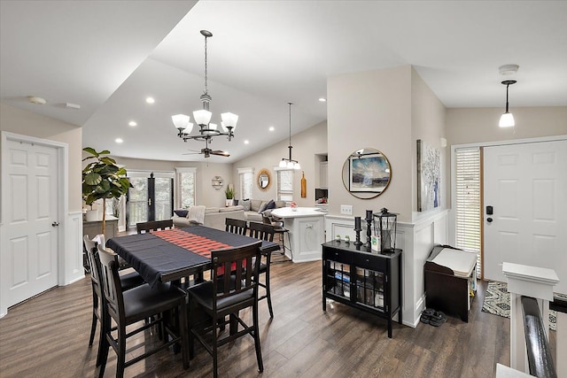 dining space featuring ceiling fan with notable chandelier, dark hardwood / wood-style flooring, and vaulted ceiling