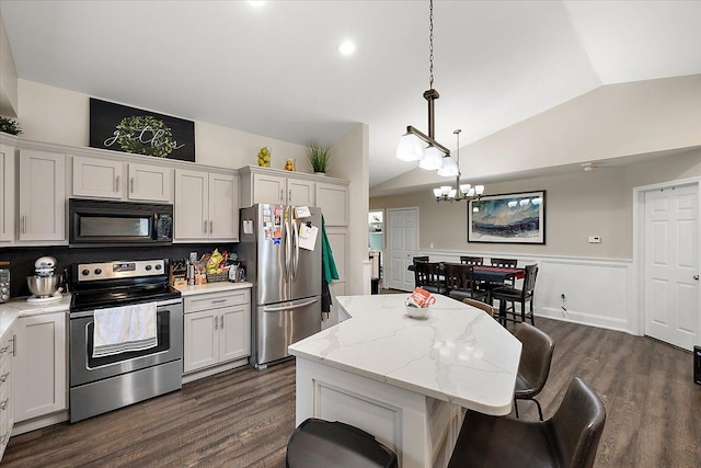 kitchen with dark wood-type flooring, white cabinets, appliances with stainless steel finishes, decorative light fixtures, and a kitchen island