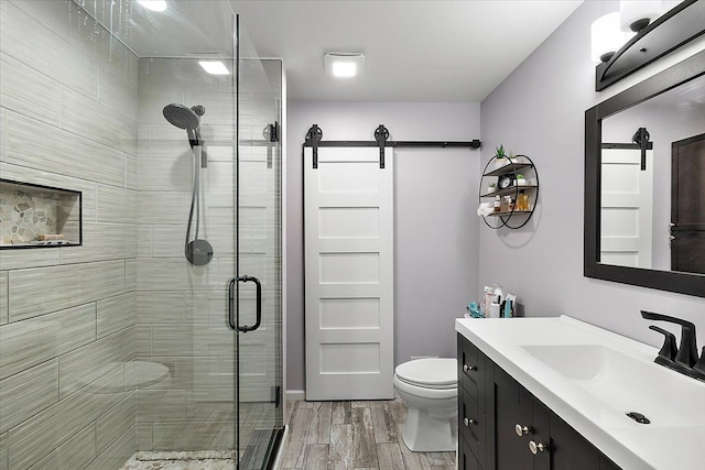 bathroom with walk in shower, toilet, vanity, and hardwood / wood-style flooring