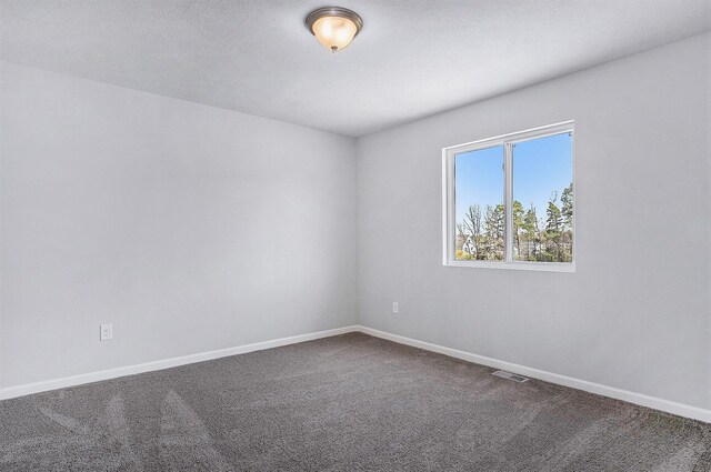 7942 Sierra Dr, Belding, MI 48809 - spare room featuring visible vents, dark carpet, and baseboards