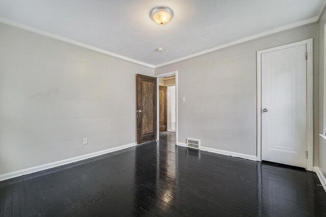 spare room with crown molding and dark wood-type flooring