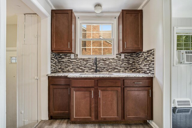 bar with light stone countertops, hardwood / wood-style floors, backsplash, and sink