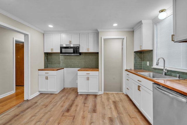 kitchen featuring appliances with stainless steel finishes, light hardwood / wood-style floors, sink, butcher block countertops, and white cabinetry