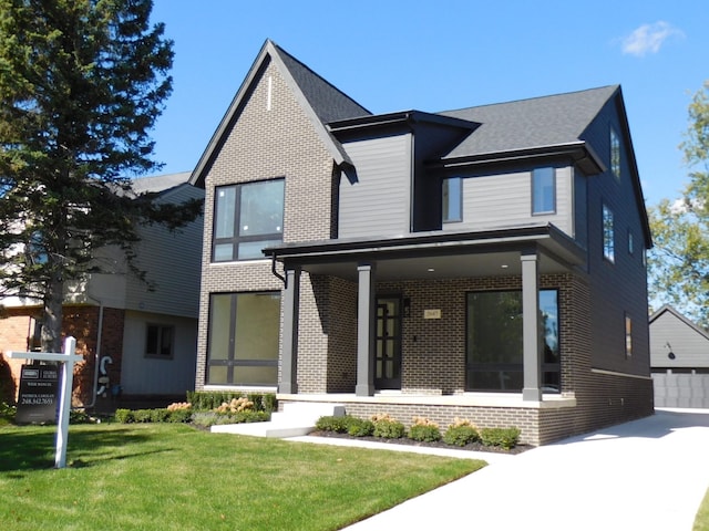 view of front of property featuring a porch, a garage, a front lawn, and an outdoor structure