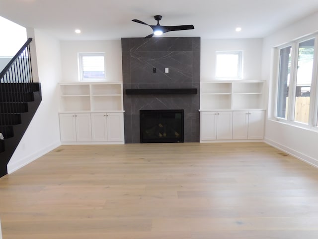 unfurnished living room featuring plenty of natural light, a high end fireplace, and light wood-type flooring