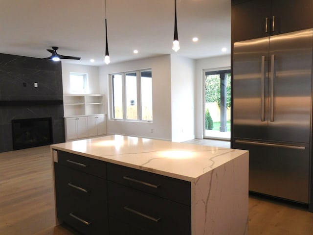 kitchen featuring a healthy amount of sunlight, a center island, built in fridge, and pendant lighting