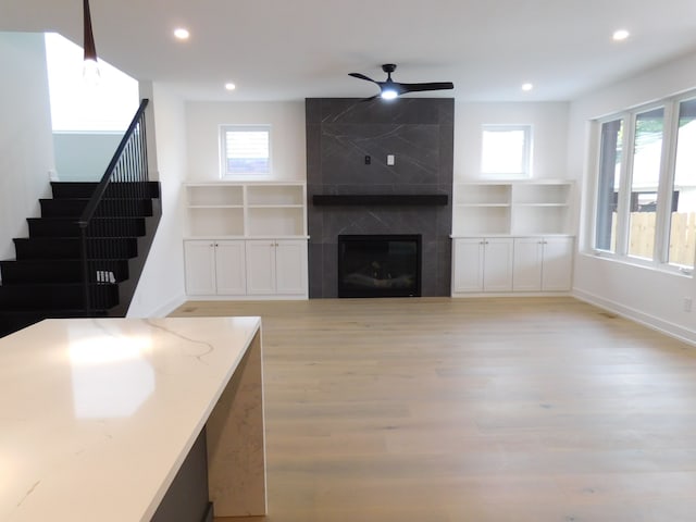 living room with a fireplace, light wood-type flooring, plenty of natural light, and ceiling fan