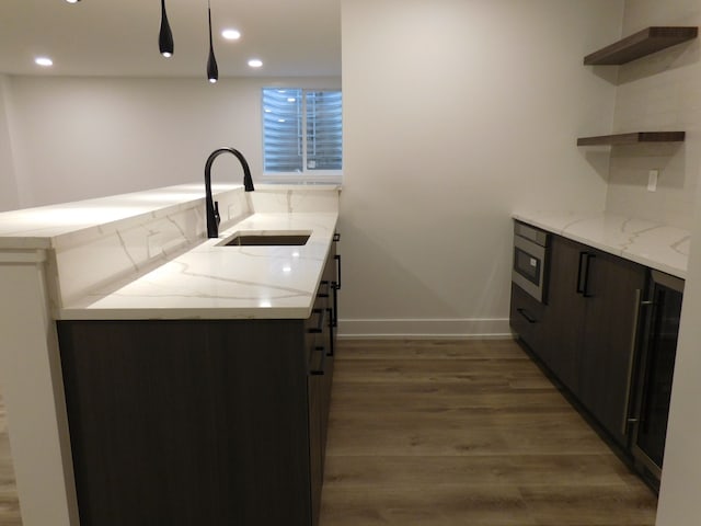 kitchen with tasteful backsplash, light stone counters, dark brown cabinetry, sink, and dark hardwood / wood-style floors