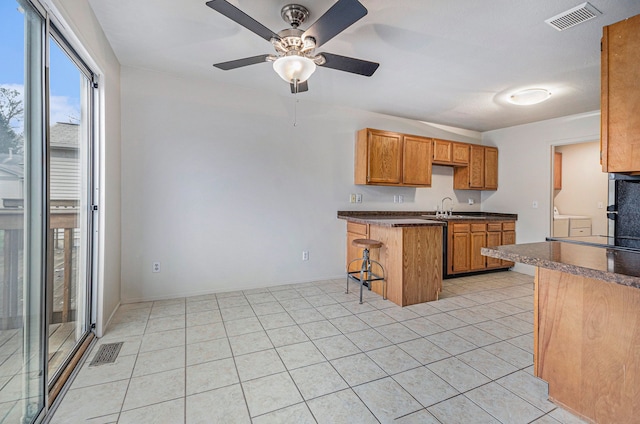 kitchen with kitchen peninsula, a breakfast bar, ceiling fan, sink, and light tile patterned floors