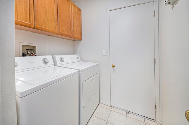 laundry room featuring cabinets, light tile patterned floors, and washer and clothes dryer