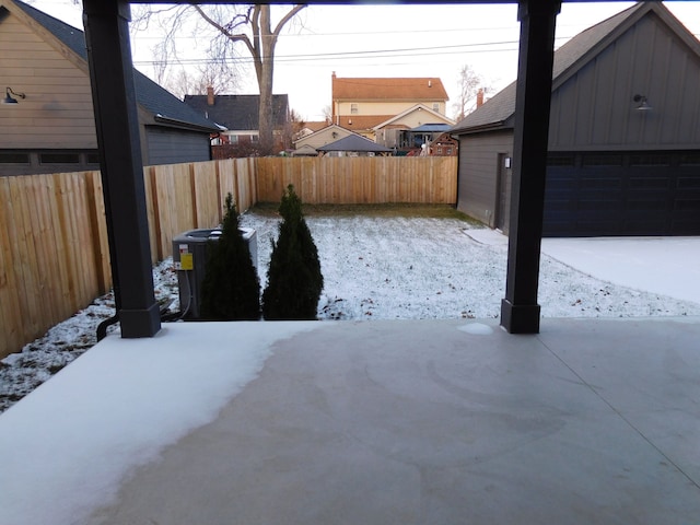 yard covered in snow featuring central AC unit, a garage, and fence