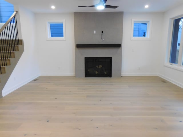 unfurnished living room featuring a large fireplace, wood finished floors, and recessed lighting