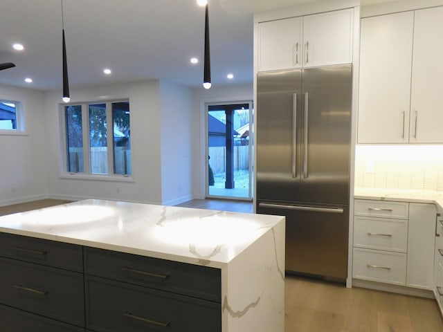 kitchen featuring light wood finished floors, light stone counters, white cabinetry, and stainless steel built in fridge