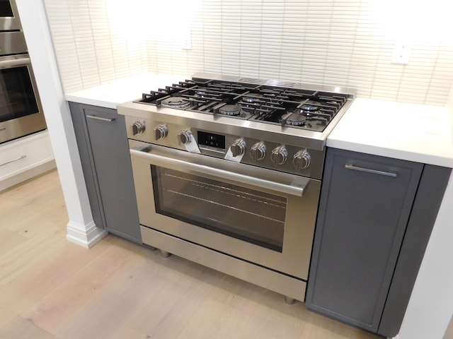 kitchen featuring tasteful backsplash, appliances with stainless steel finishes, light countertops, gray cabinetry, and light wood-style floors