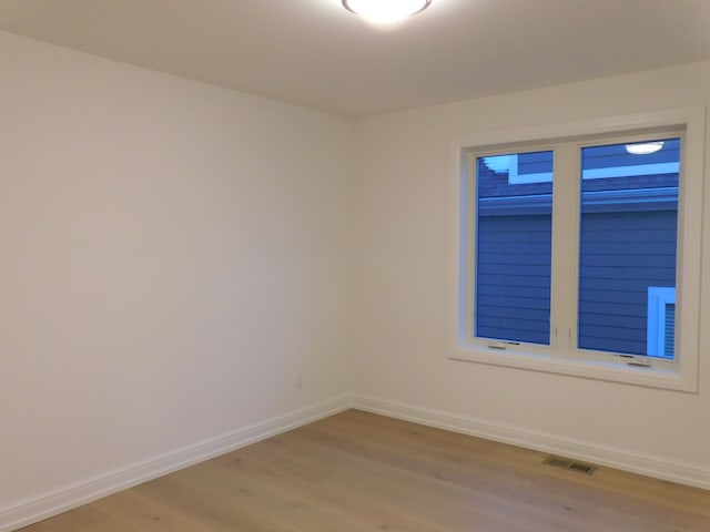 empty room featuring light wood-type flooring, visible vents, and baseboards