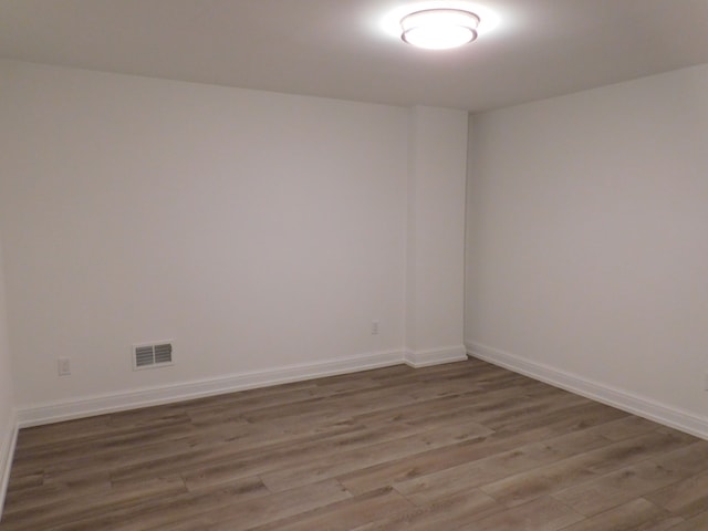 empty room featuring visible vents, baseboards, and wood finished floors