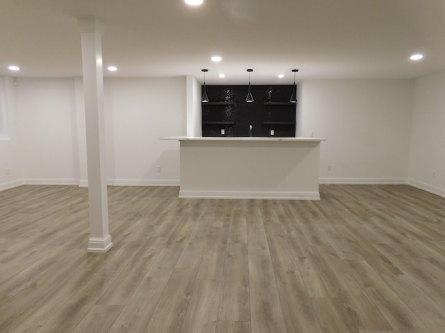 finished below grade area with light wood-style flooring, baseboards, indoor bar, and recessed lighting