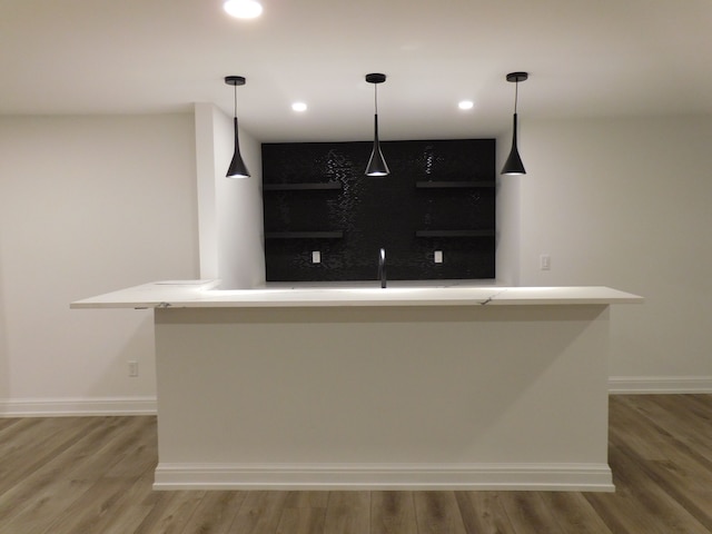 bar with hanging light fixtures, light wood-style floors, baseboards, and recessed lighting