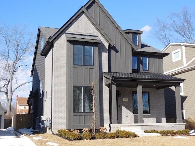 view of front of house with brick siding, covered porch, board and batten siding, a standing seam roof, and metal roof