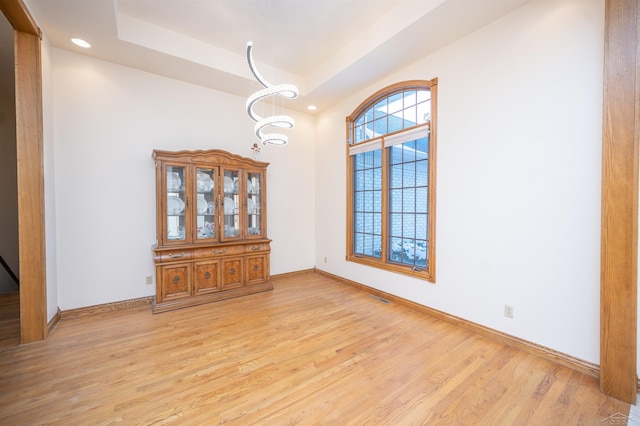 interior space featuring a notable chandelier, a tray ceiling, and light hardwood / wood-style flooring