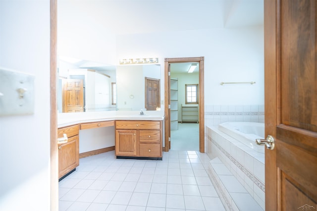 bathroom with tile patterned flooring, vanity, and tiled bath