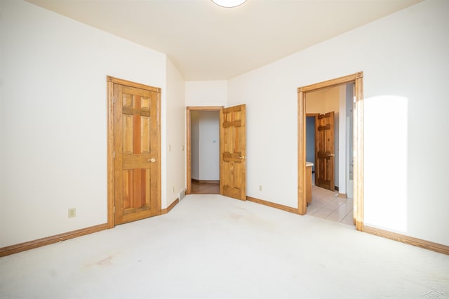 unfurnished bedroom with light colored carpet and connected bathroom