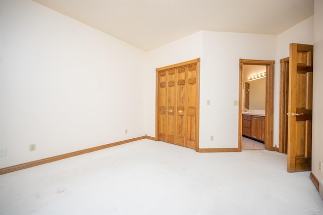 unfurnished bedroom with light carpet, connected bathroom, and a closet