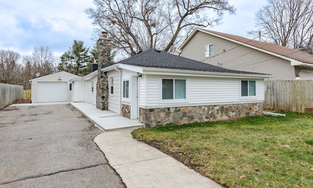 view of home's exterior with a lawn, a garage, and an outbuilding