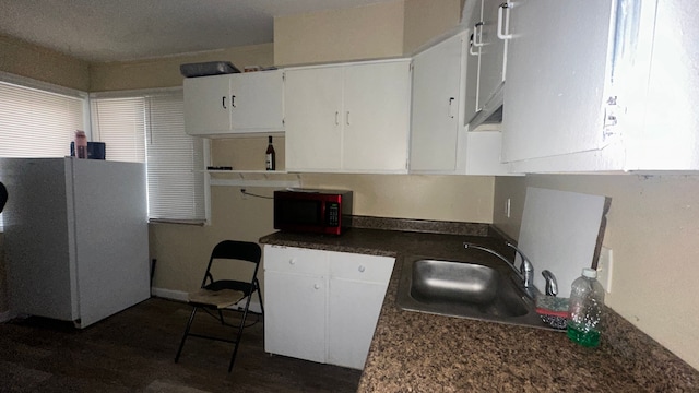 kitchen with a textured ceiling, dark wood-type flooring, sink, white fridge, and white cabinetry