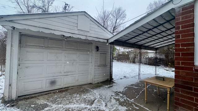 snow covered garage with a carport