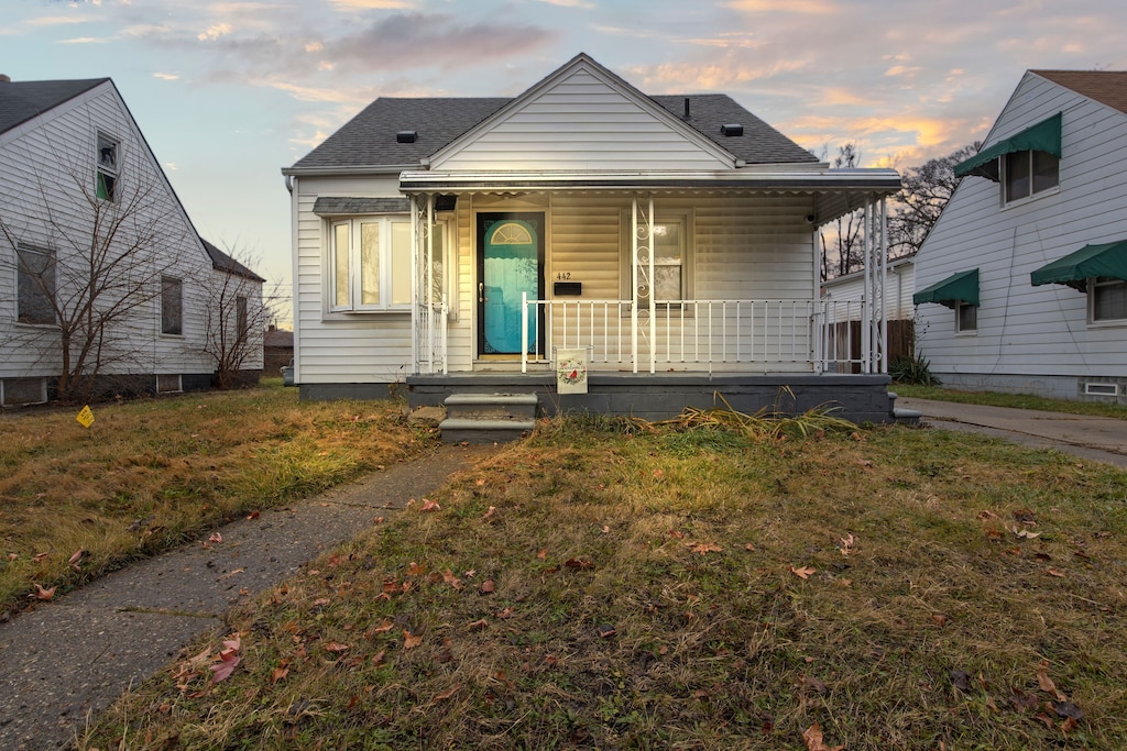 bungalow with covered porch and a yard