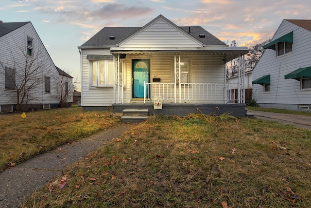 bungalow with covered porch and a yard