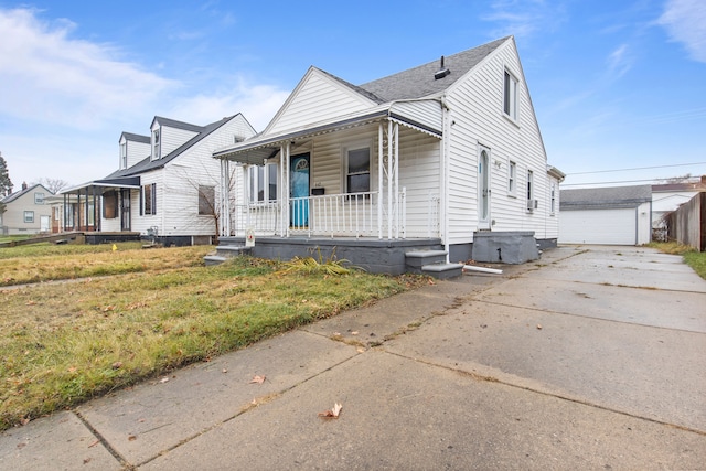 view of front of home featuring an outbuilding, covered porch, a front yard, and a garage