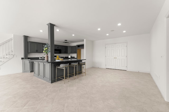 kitchen with a breakfast bar, a center island, gray cabinetry, and light tile patterned flooring