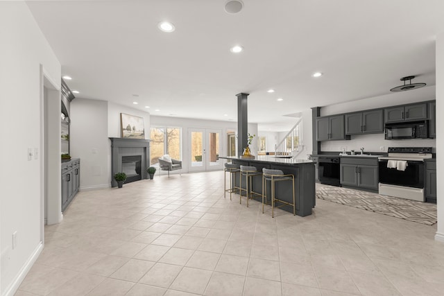 kitchen with gray cabinetry, a center island, sink, a kitchen breakfast bar, and black appliances