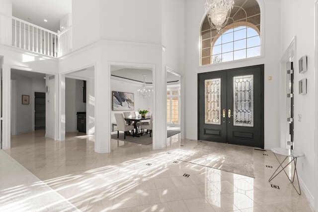 foyer entrance featuring a chandelier, a high ceiling, and french doors