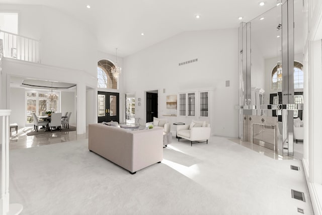 carpeted living room with french doors, high vaulted ceiling, a healthy amount of sunlight, and a notable chandelier