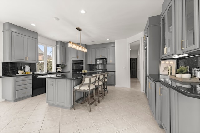 kitchen featuring backsplash, gray cabinetry, a center island, and black appliances