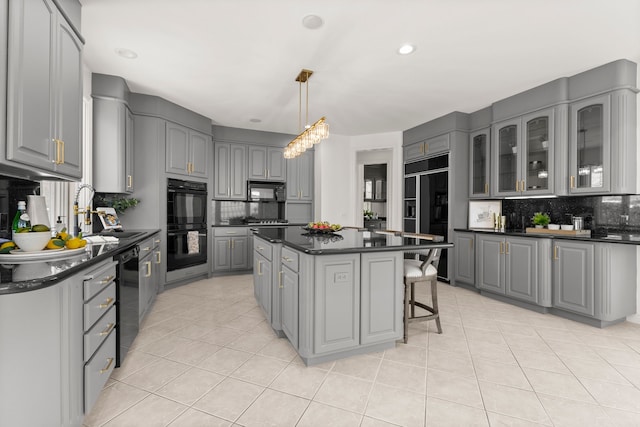 kitchen with gray cabinetry, black appliances, decorative backsplash, light tile patterned floors, and a kitchen island