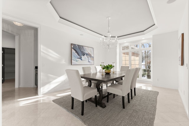 dining area with a tray ceiling, a notable chandelier, and ornamental molding