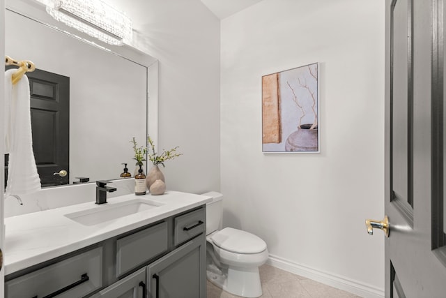 bathroom with toilet, tile patterned flooring, vanity, and an inviting chandelier