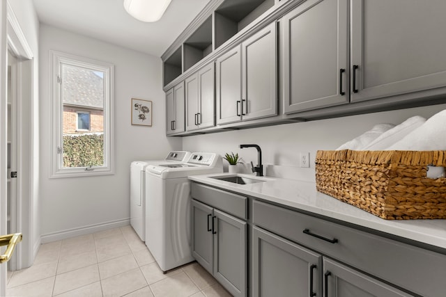 clothes washing area with light tile patterned flooring, cabinets, sink, and washing machine and clothes dryer