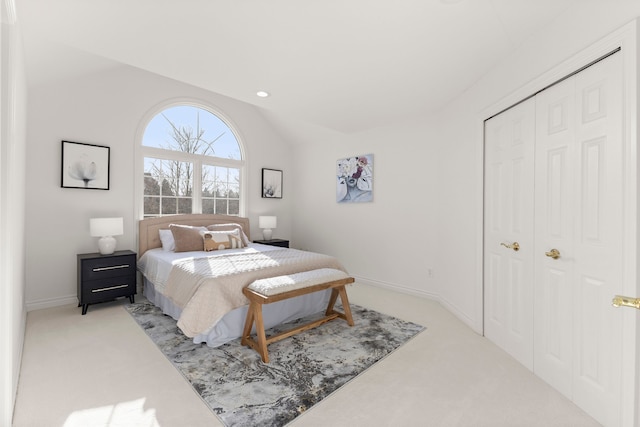 carpeted bedroom with lofted ceiling and a closet